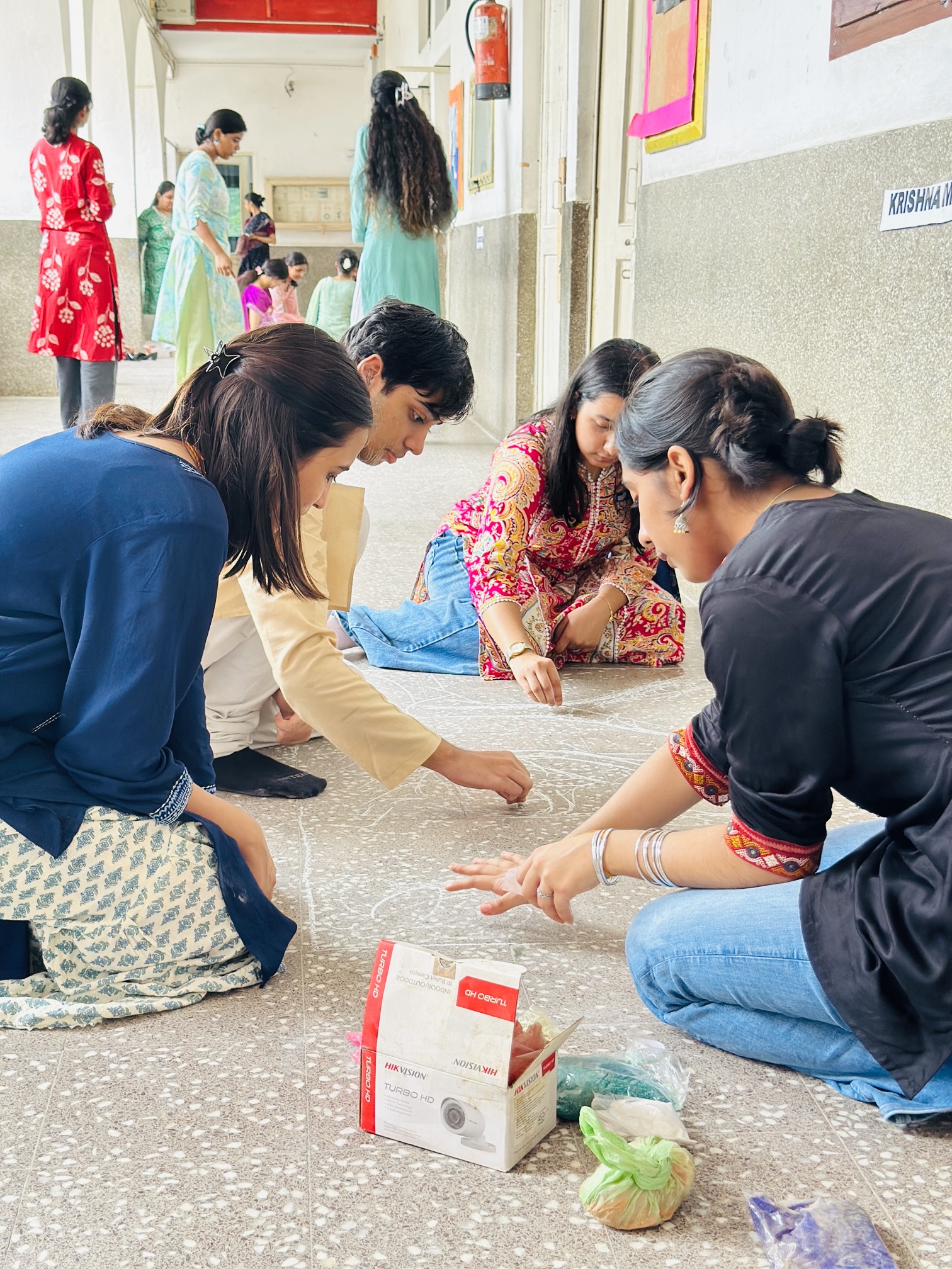 Senior students completing an intricate rangoli design for Janmashtami 2026